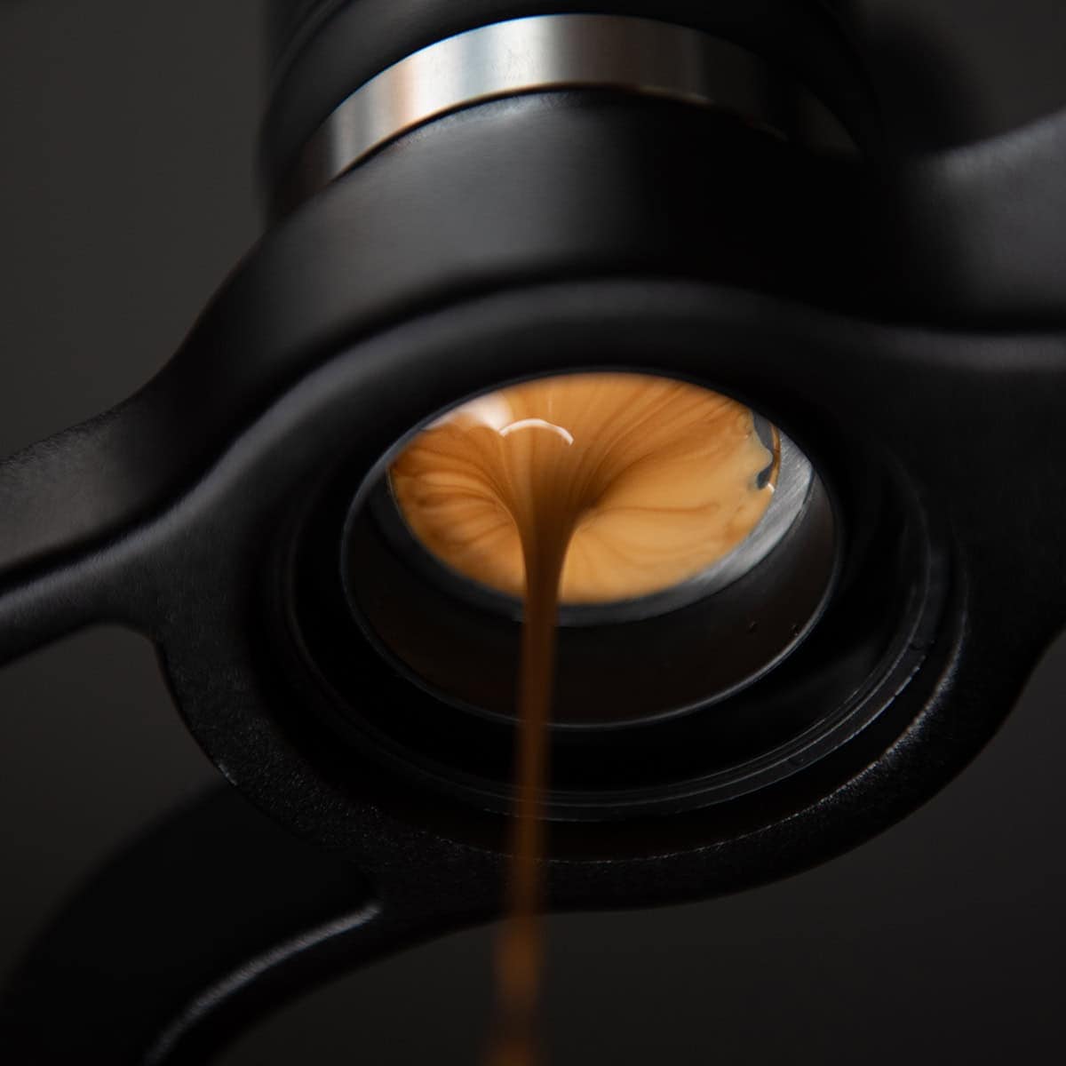 Espresso being poured from a portafilter on a dark background with the Flair 2GO manual espresso maker.