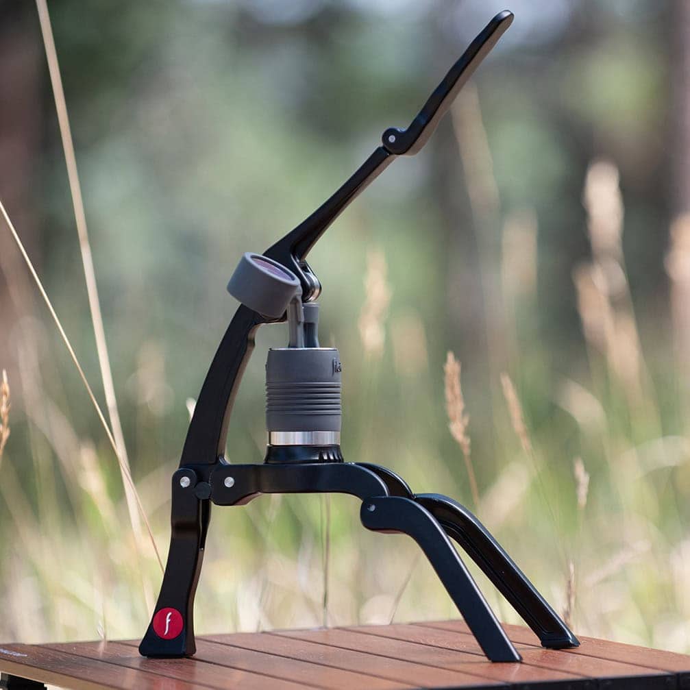 Flair 2GO manual espresso maker on a wooden table outside.