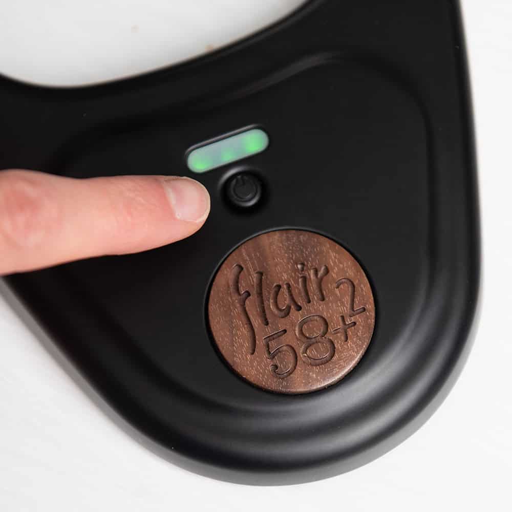 Close-up of the Flair 58 Plus 2 preheat control system with branding and a finger pressing a button.