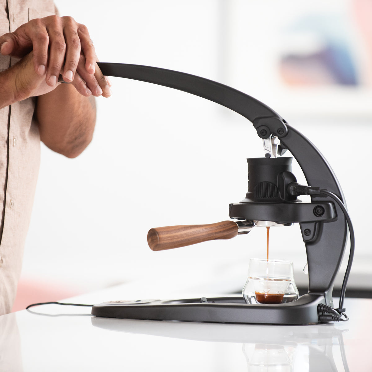 Flair 58 Plus 2 manual lever espresso maker being used with a blurred background