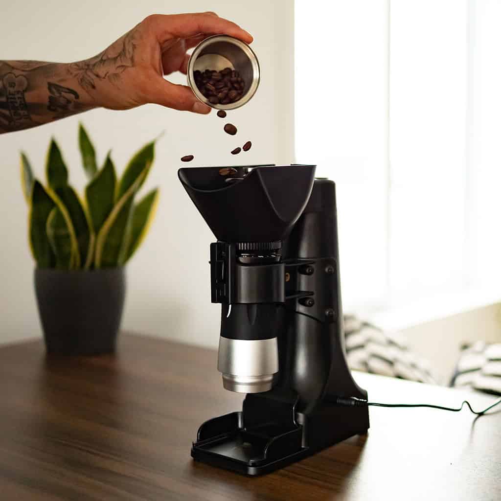 Flair Power Tower on a counter with a man adding coffee beans for grinding