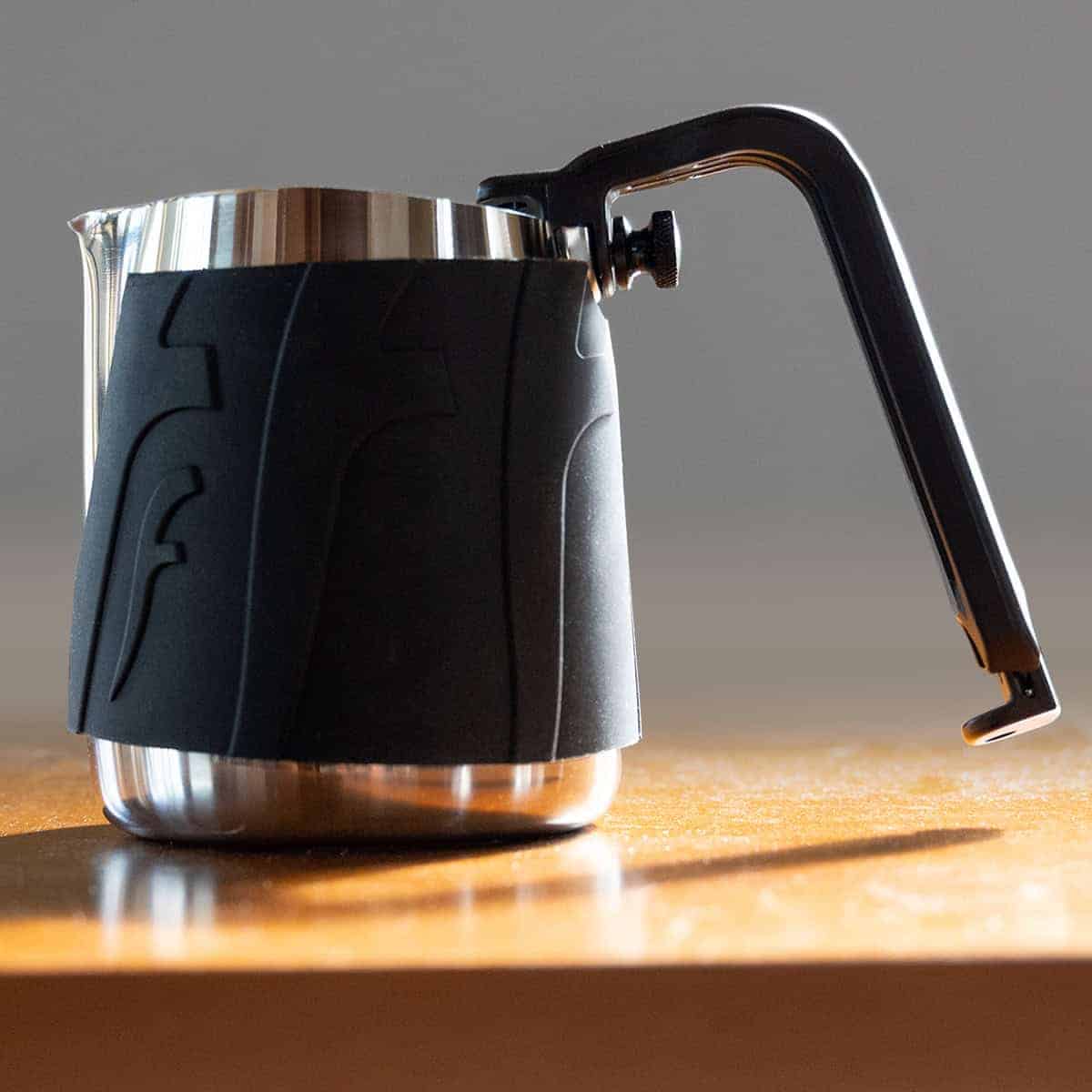 Flair Milk Pitcher with handle on a wooden table.