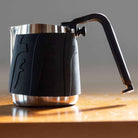 Flair Milk Pitcher with handle on a wooden table.