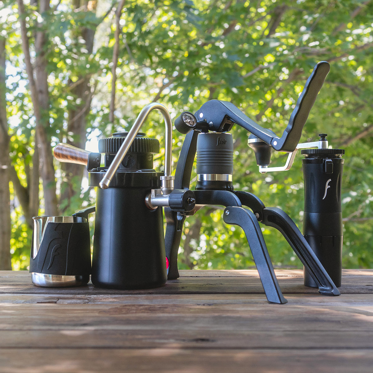 Outdoor photo showing the items in the Steam Travel Kit including the Flair 2GO, Royal Grinder, Wizard Steamer and Milk Pitcher.