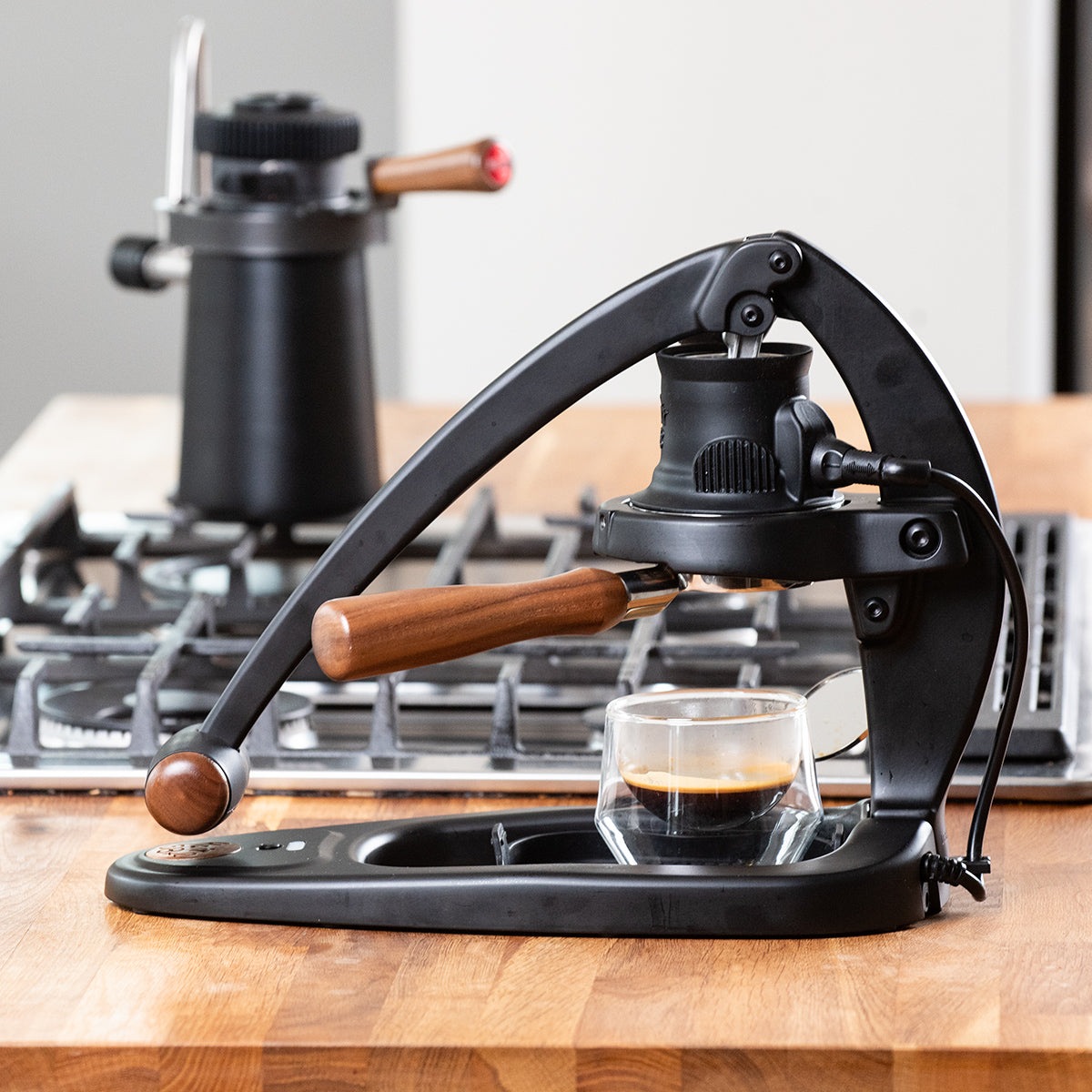 Manual coffee press on a kitchen counter with a glass of coffee.