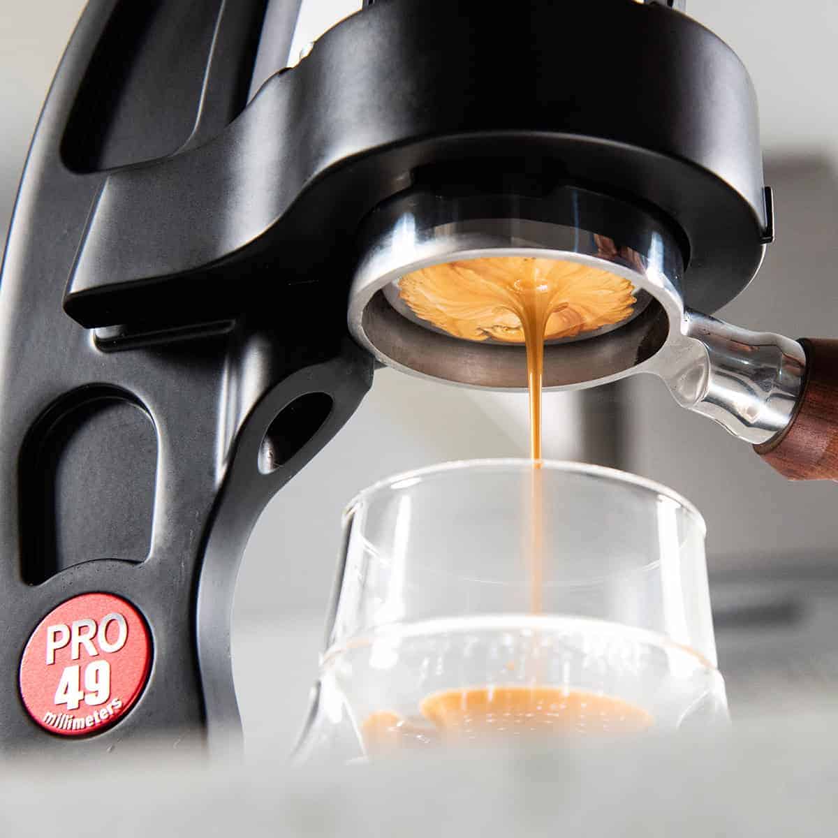 Espresso being brewed into a glass from the Flair 49 PRO manual espresso machine with 'PRO 49' branding.