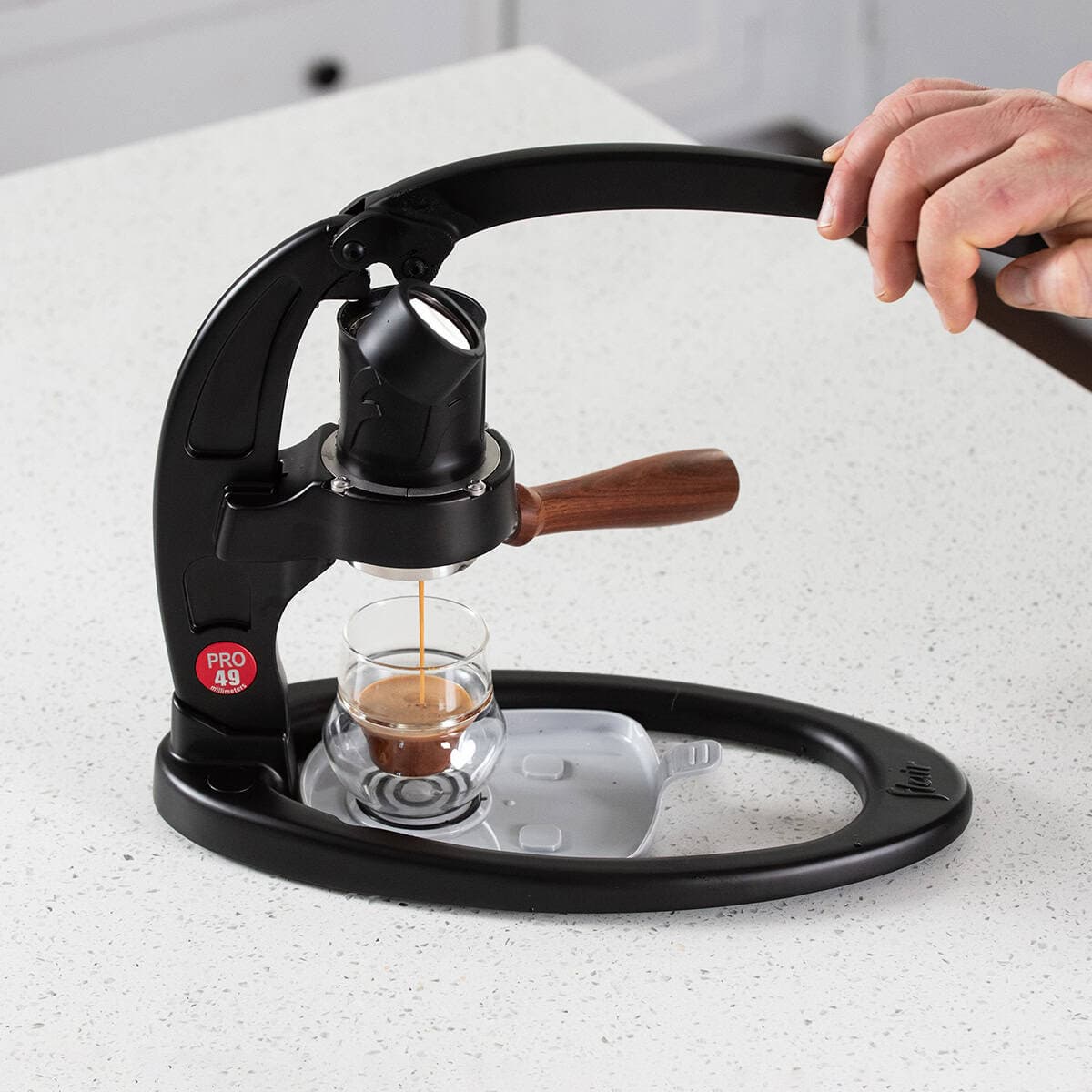 The Flair 49 PRO manual lever espresso maker brewing espresso on a counter.