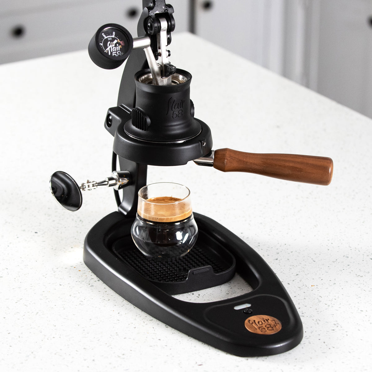 Flair 58 Plus 2 manual espresso maker on a white counter with the lever raised.