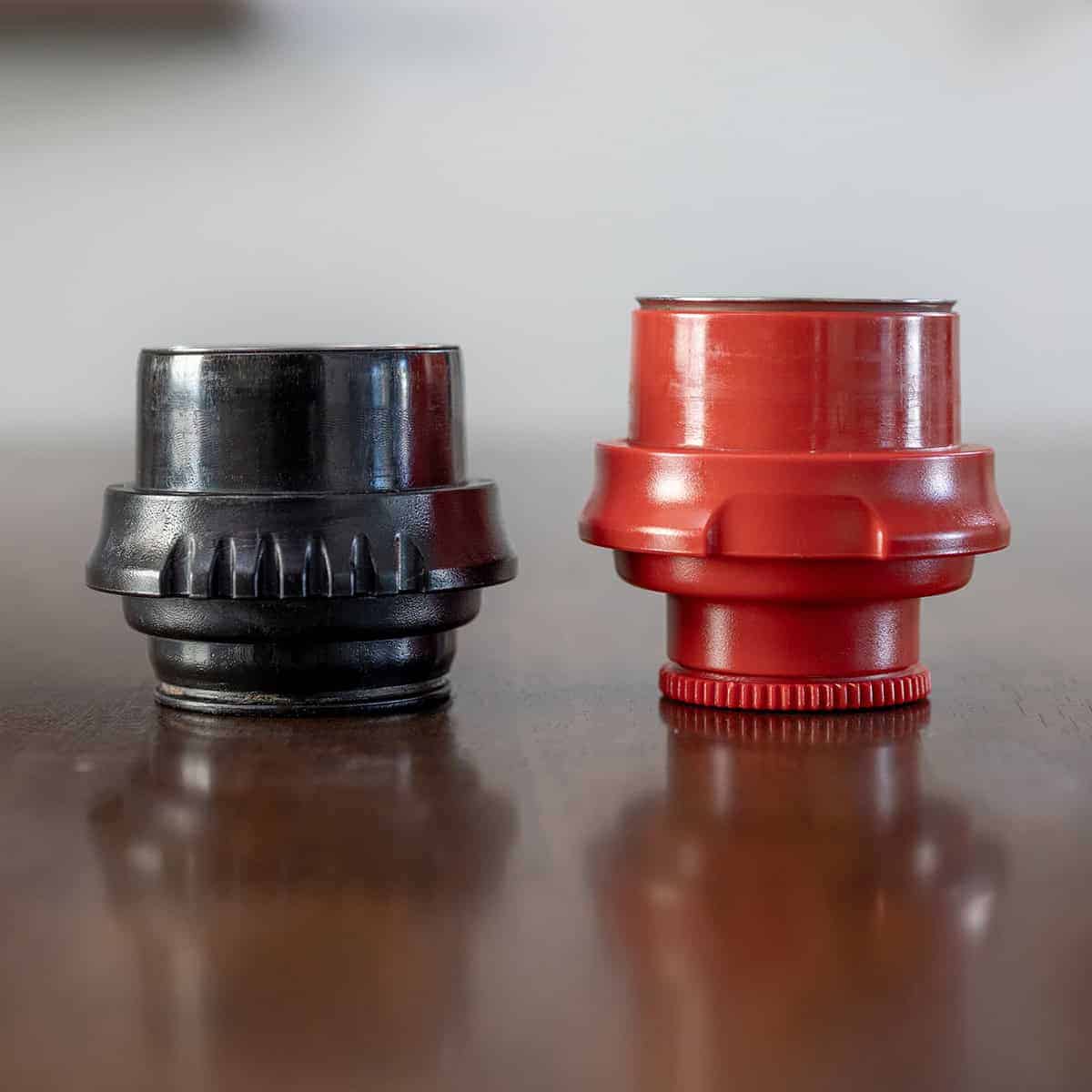 Black bottomless portafilter and red flow control portafilter that come standard with the Flair Classic manual espresso maker.