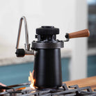 Flair Wizard Steamer on a gas stovetop with a flame.